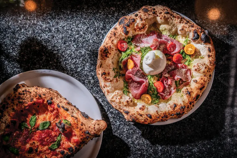 Nápolyi pizza burratával, sonkával és koktélparadicsommal, mellette calzone